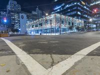an empty street near a building at night with no traffic lights in the foreground