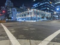 an empty street near a building at night with no traffic lights in the foreground