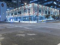 an empty street near a building at night with no traffic lights in the foreground