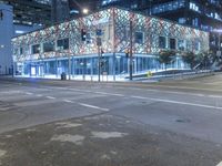 an empty street near a building at night with no traffic lights in the foreground