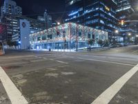 an empty street near a building at night with no traffic lights in the foreground