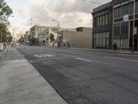 a long empty street in the middle of a city, with a light rail on the pole