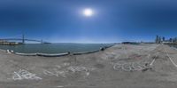 a fish eye view of an ocean with graffiti writing on it and a bridge in the background