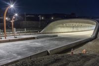 an empty tunnel is illuminated by street lights at night in a city park - like setting