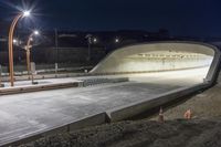 an empty tunnel is illuminated by street lights at night in a city park - like setting