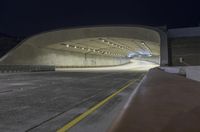 a large concrete tunnel that is open and empty at night with street lights on the corner