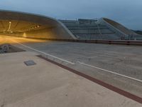 a large concrete tunnel that is near a train track at night time in europe as the sun begins