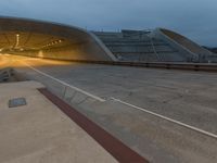 a large concrete tunnel that is near a train track at night time in europe as the sun begins