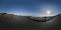 a panoramic photograph looking down a curved road at a sunrise in the distance