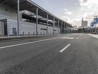 the empty street has long poles near it in front of the building of the building