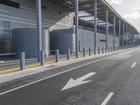 the empty street has long poles near it in front of the building of the building