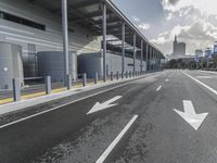 the empty street has long poles near it in front of the building of the building