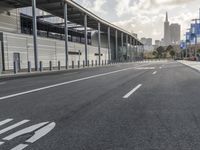 the empty street has long poles near it in front of the building of the building