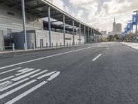 the empty street has long poles near it in front of the building of the building
