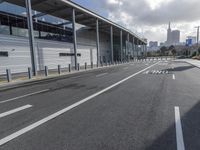 the empty street has long poles near it in front of the building of the building