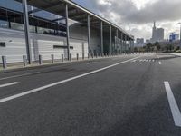 the empty street has long poles near it in front of the building of the building