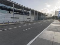 the empty street has long poles near it in front of the building of the building