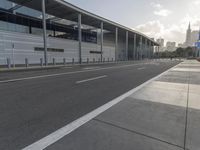 the empty street has long poles near it in front of the building of the building