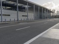 the empty street has long poles near it in front of the building of the building