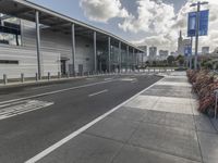 the empty street has long poles near it in front of the building of the building