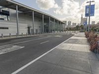 the empty street has long poles near it in front of the building of the building