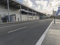 the empty street has long poles near it in front of the building of the building