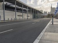the empty street has long poles near it in front of the building of the building