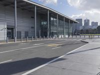 the empty street has long poles near it in front of the building of the building