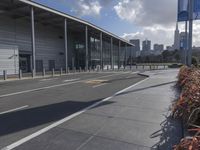 the empty street has long poles near it in front of the building of the building