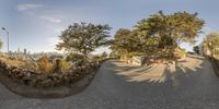 a 360 - view picture of a very narrow road in the city with buildings, trees and bushes behind it