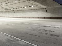 the floor of an empty concrete structure with lights and track markings in the foreground