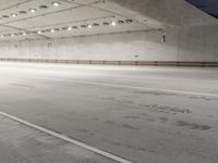 the floor of an empty concrete structure with lights and track markings in the foreground