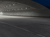 the floor of an empty concrete structure with lights and track markings in the foreground