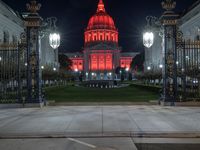 a street is in front of some ornate pillars and a red building with a dome