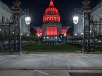 a street is in front of some ornate pillars and a red building with a dome