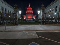 a street is in front of some ornate pillars and a red building with a dome