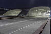 an empty highway at night time with the lights on and a view of mountains in the distance