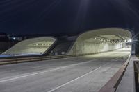 an empty highway at night time with the lights on and a view of mountains in the distance