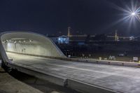 an empty highway going into a tunnel at night with lights on and on a building in the background