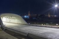 an empty highway going into a tunnel at night with lights on and on a building in the background