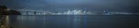 view of the bay with buildings in the background and water under it at night with an overcast sky