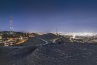 three men at the top of a hill looking at a city below them at night