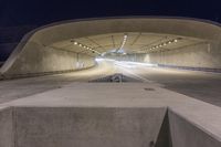 the car is driving through this tunnel as it passes underneath the road at night time