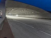 an empty highway in a tunnel with the lights on and the road lined up at the end