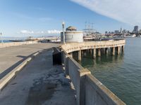 a pier and a white light on a partly clear day of day time with buildings in the background