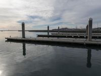 a dock surrounded by wooden boards in the water and birds on the dock nearby to the water
