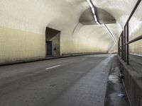an empty roadway under a building with a white light on one corner and a tan and black wall and ceiling