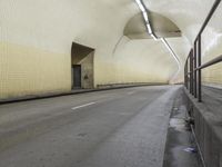 an empty roadway under a building with a white light on one corner and a tan and black wall and ceiling