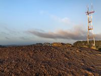 there is a large mound of dirt next to a radio tower with a antenna on the top of it