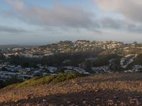 a man riding a horse on a hillside next to the city with houses below it